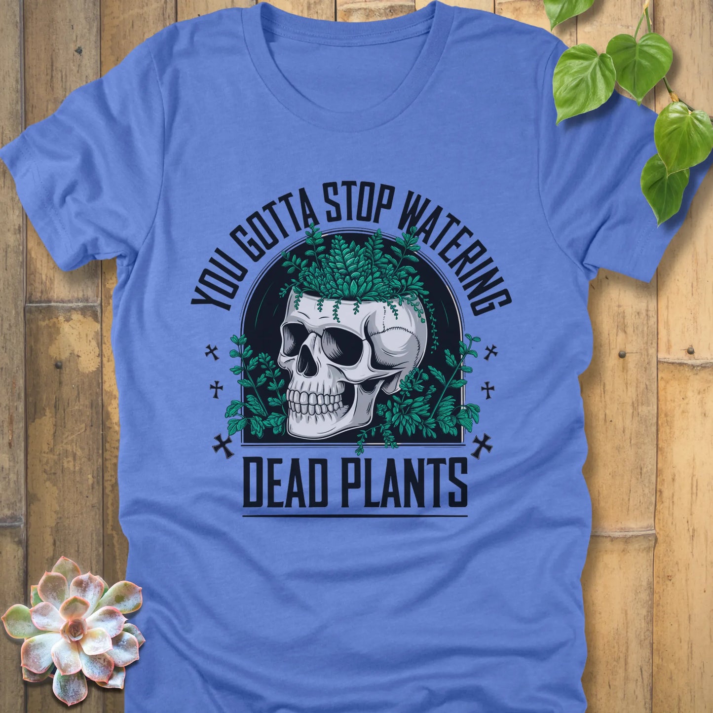 Heather Colombia Blue t-shirt featuring the design “You gotta stop watering dead plants” printed in black letters with skull and plants graphic