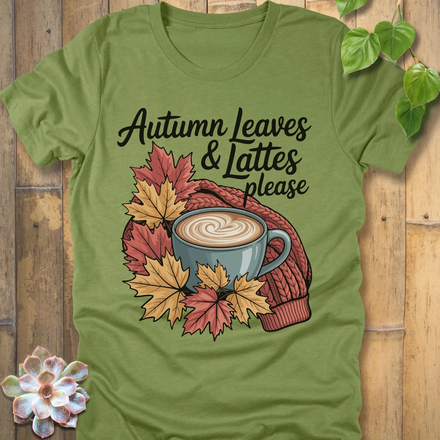 Heather Green t-shirt featuring the design Autumn Leaves & Lattes printed in black letters with a mug of coffee and leaves