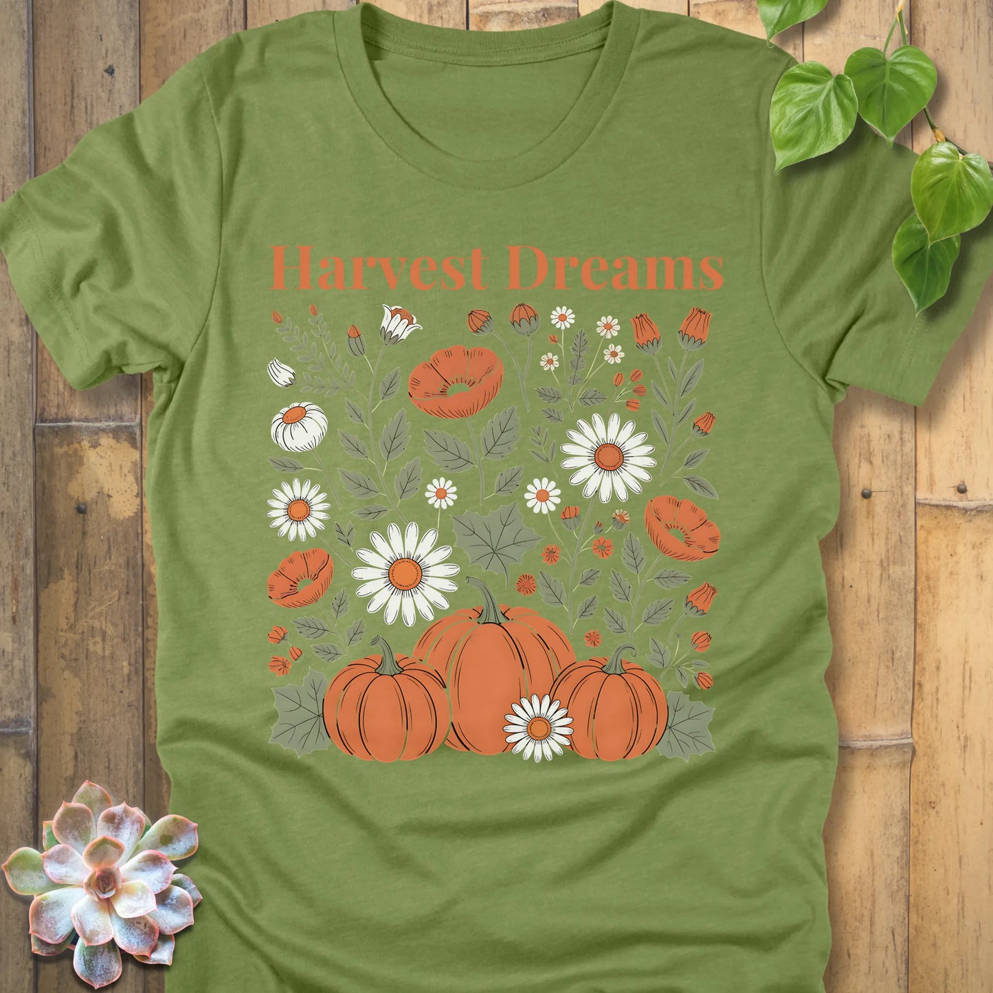 Heather Green t-shirt featuring the design Harvest Dreams printed in orange letters flowers and pumpkin