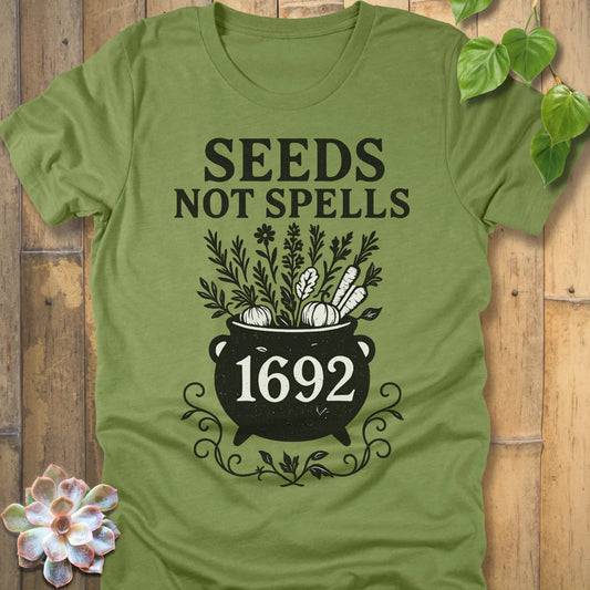 Heather Green t-shirt featuring the design Seeds Not Spells printed in bold black letters, halloween gardening graphic tee.