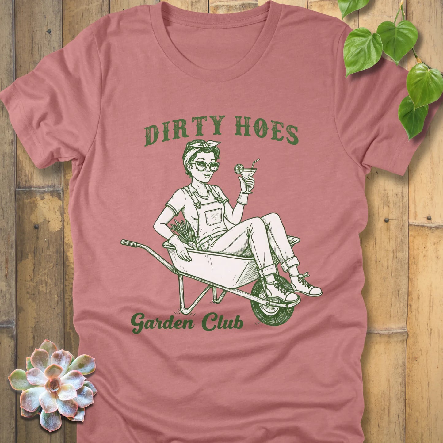 Heather Mauve t-shirt featuring the design Dirty Hoes, Garden Club printed in green letters with a girl in the trolley, gardening graphic tee.