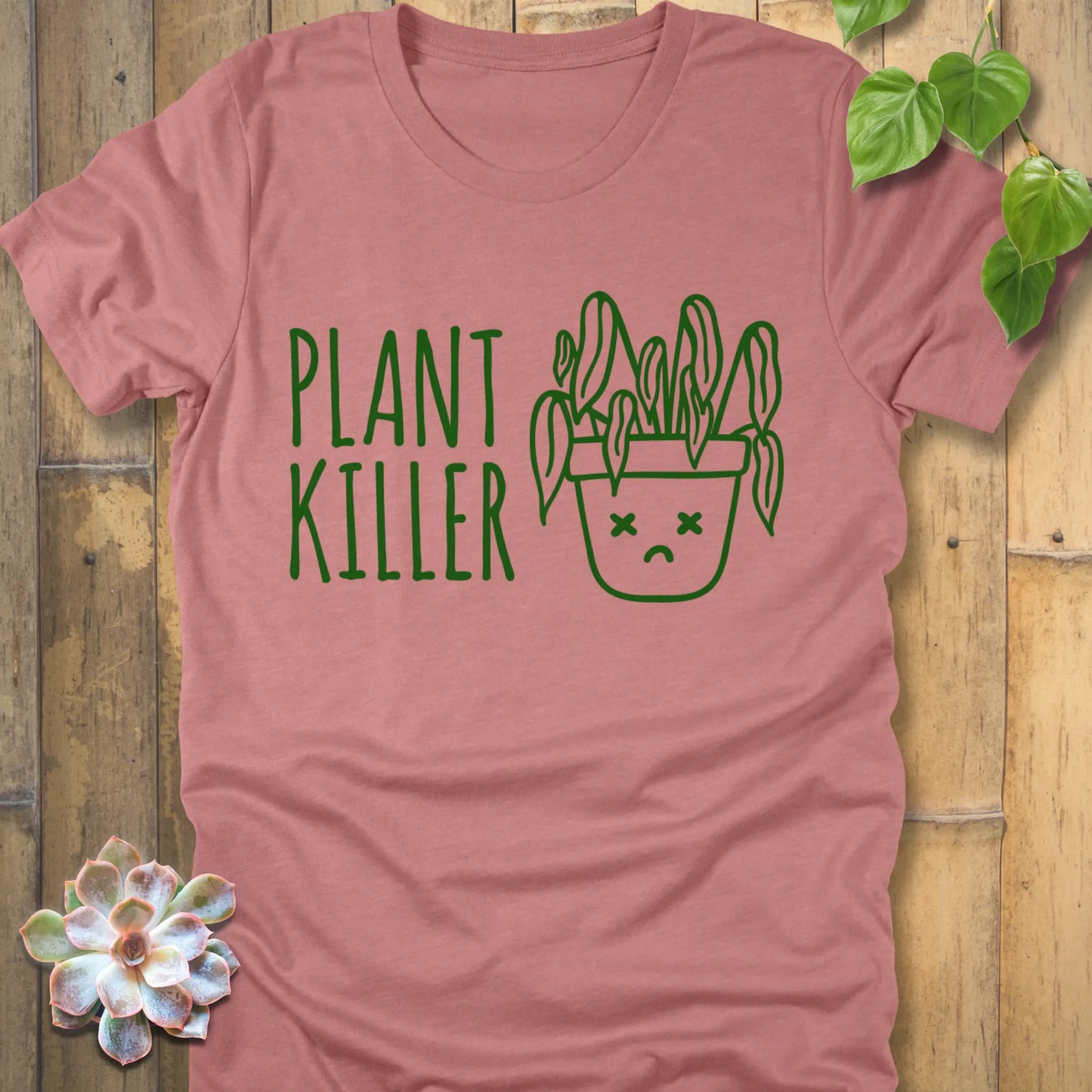 Heather Mauve t-shirt featuring the design Plant Killer printed in green letters with a plant in an emoji pot 