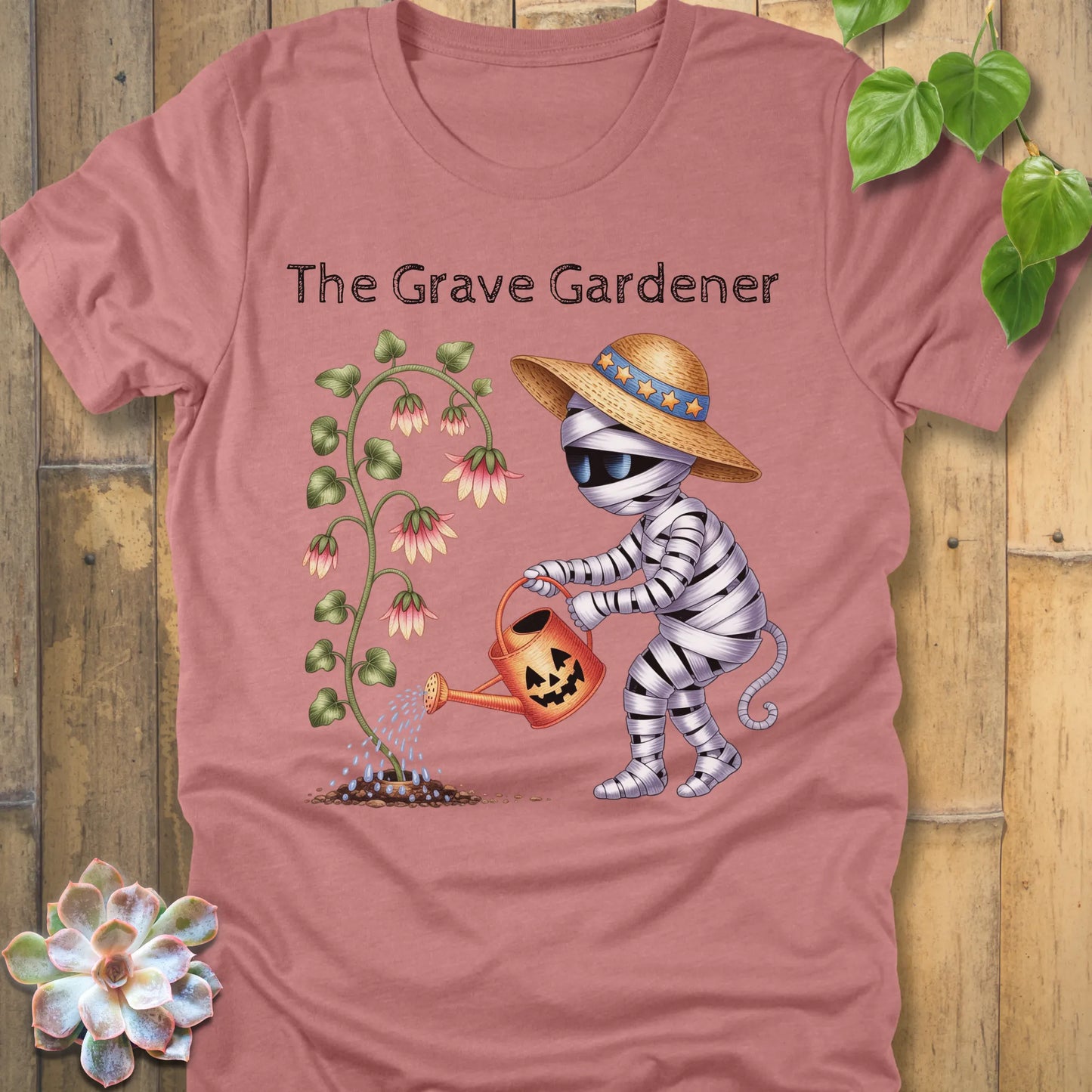 Heather Mauve t-shirt featuring the design The Grave Gardener printed in bold black letters and a ghost watering the plant