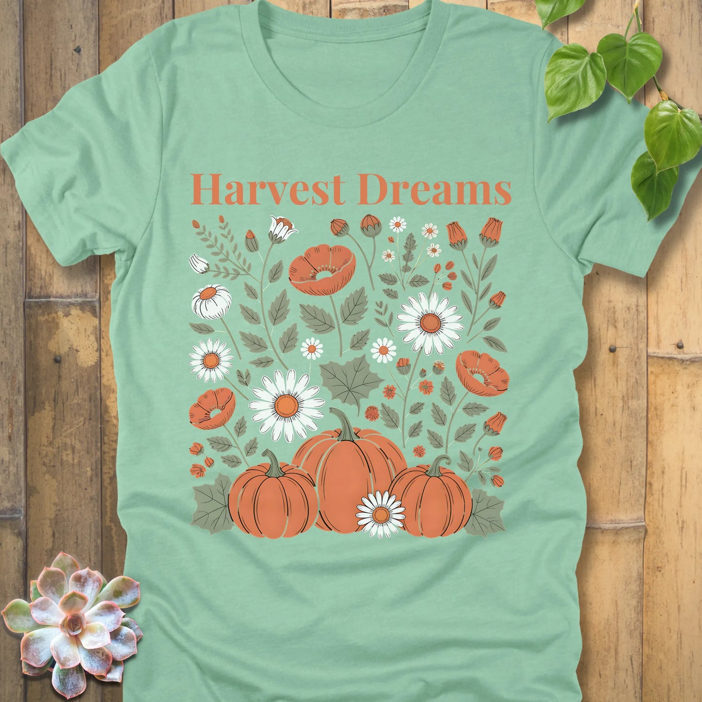 Heather Mint t-shirt featuring the design Harvest Dreams printed in orange letters flowers and pumpkin