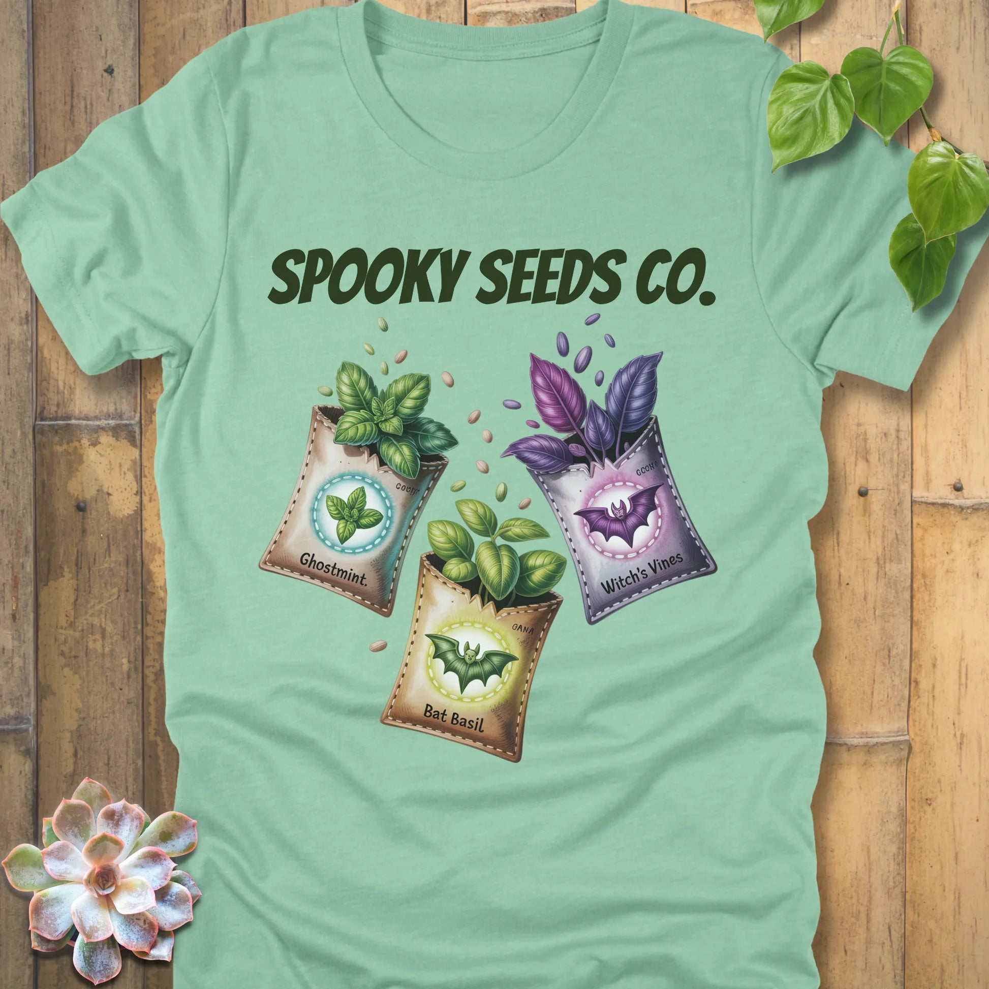 Heather Mint t-shirt featuring the design Spooky Seeds Co. printed in bold letters  and a halloween design and plants