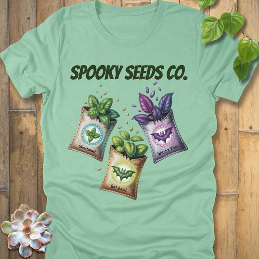 Heather Mint t-shirt featuring the design Spooky Seeds Co. printed in bold letters  and a halloween design and plants