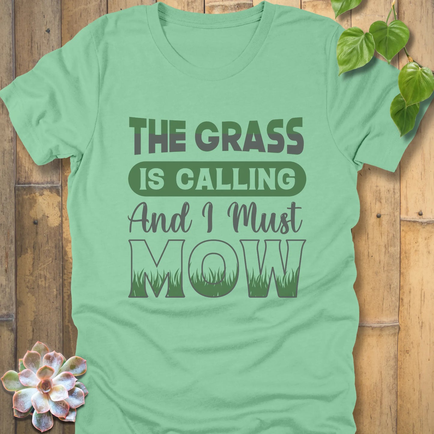 Heather Mint t-shirt featuring the design The Grass is Calling and I Must Mow in bold letters and with grass