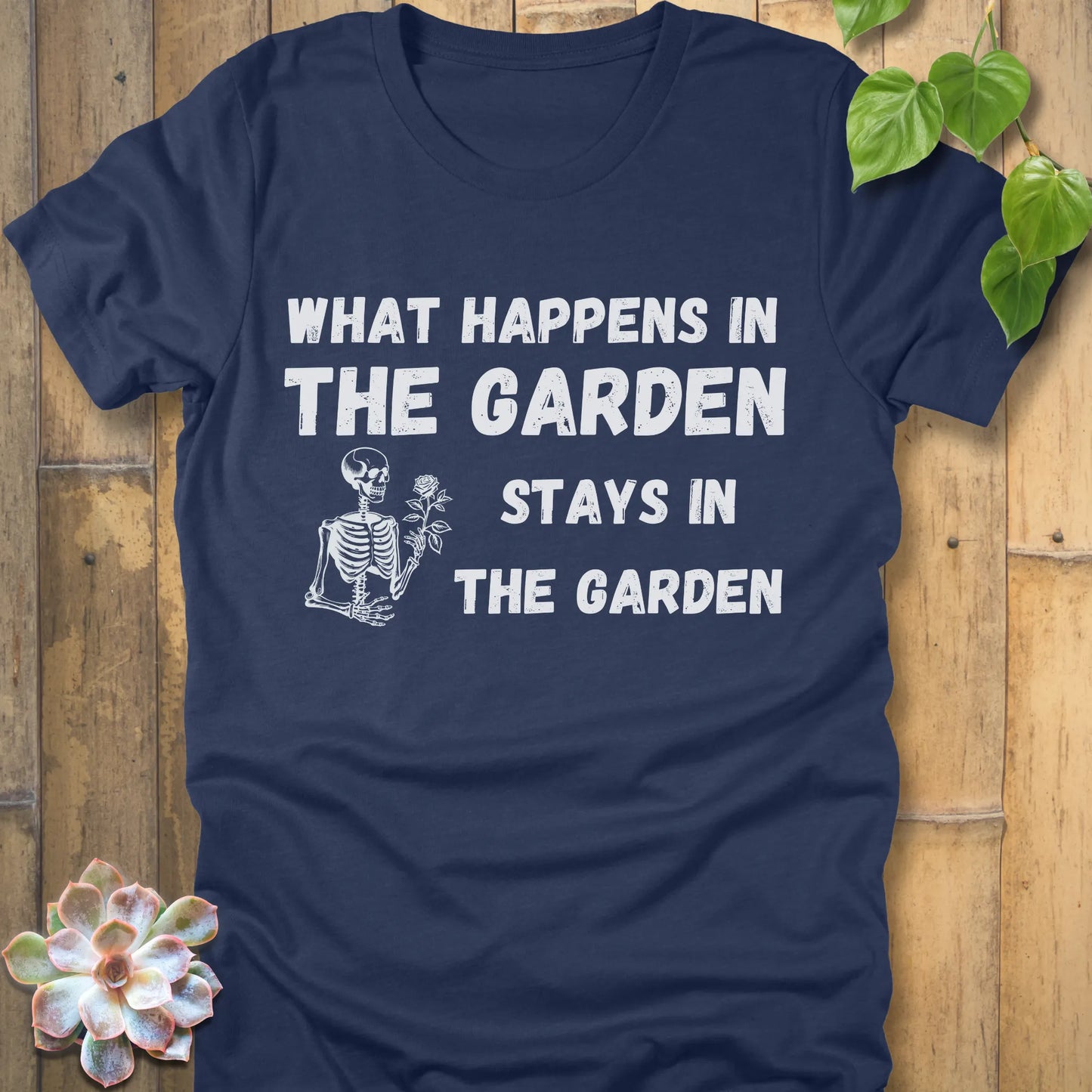 Heather Navy t-shirt featuring the design What Happens In The Garden Stays In The Garden printed in bold letters with skeleton and flower