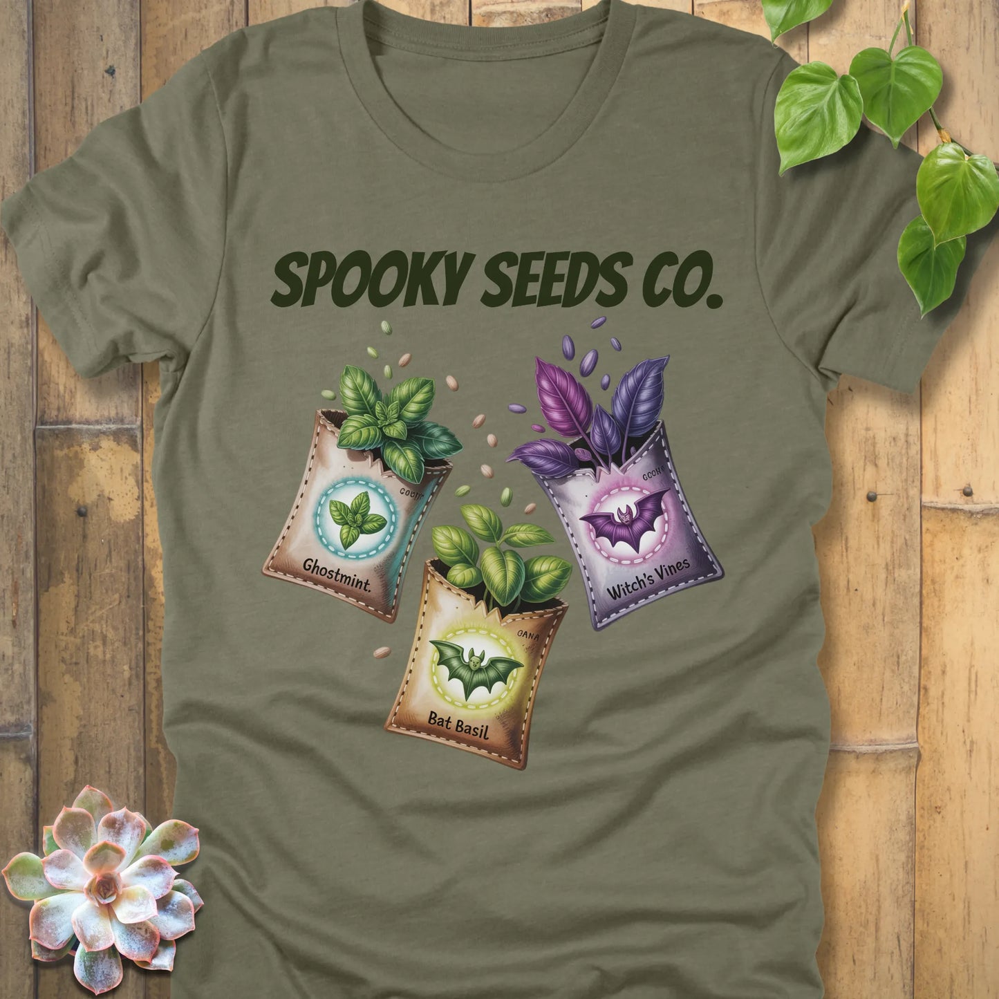 Heather Olive t-shirt featuring the design Spooky Seeds Co. printed in bold letters  and a halloween design and plants