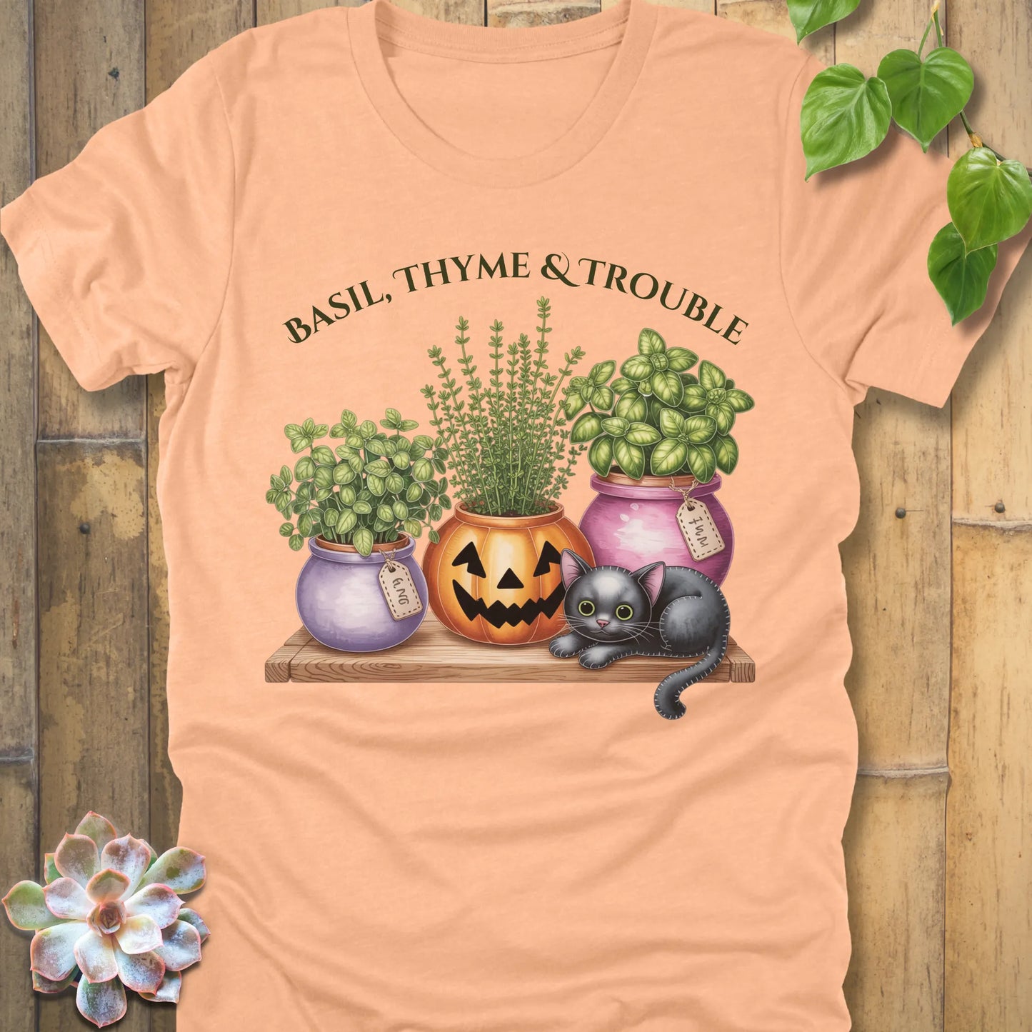 Heather Peach t-shirt featuring the design "Basil, Thyme & Trouble" printed in bold green letters and a plants, cats 
