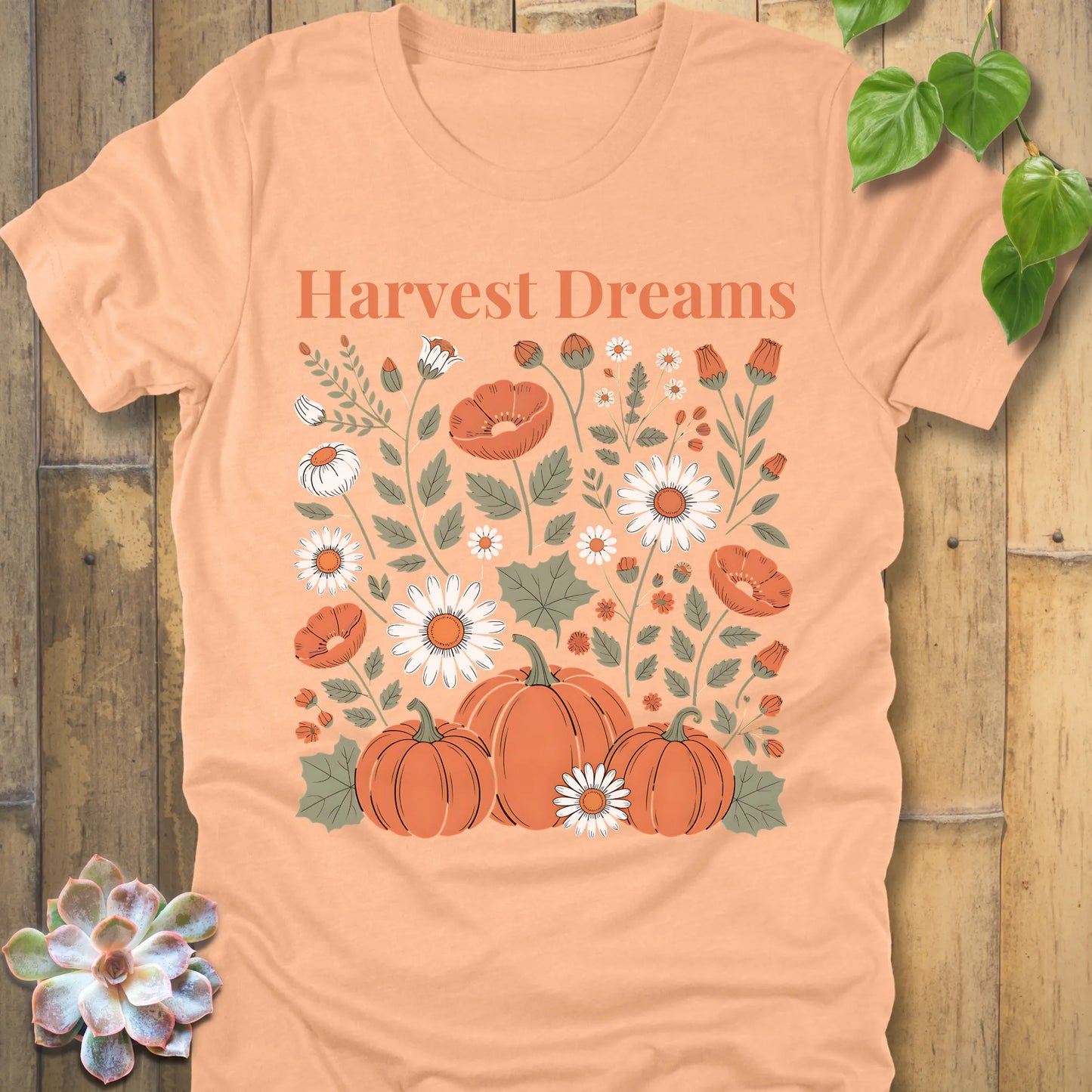 Heather Peach t-shirt featuring the design Harvest Dreams printed in orange letters flowers and pumpkin