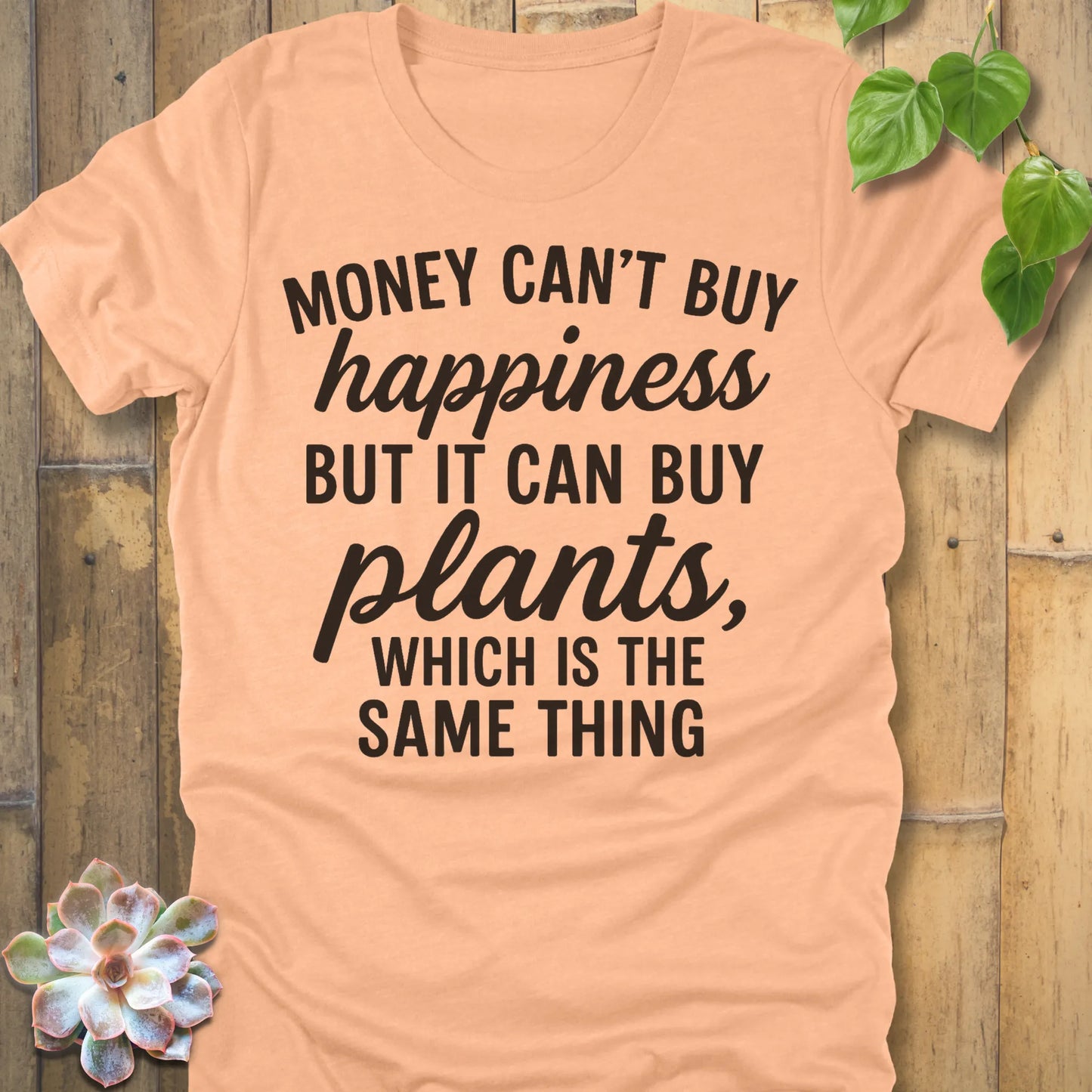 Heather Peach t-shirt featuring the design Money Can’t Buy Happiness printed in bold black letters, motivational quote shirt.