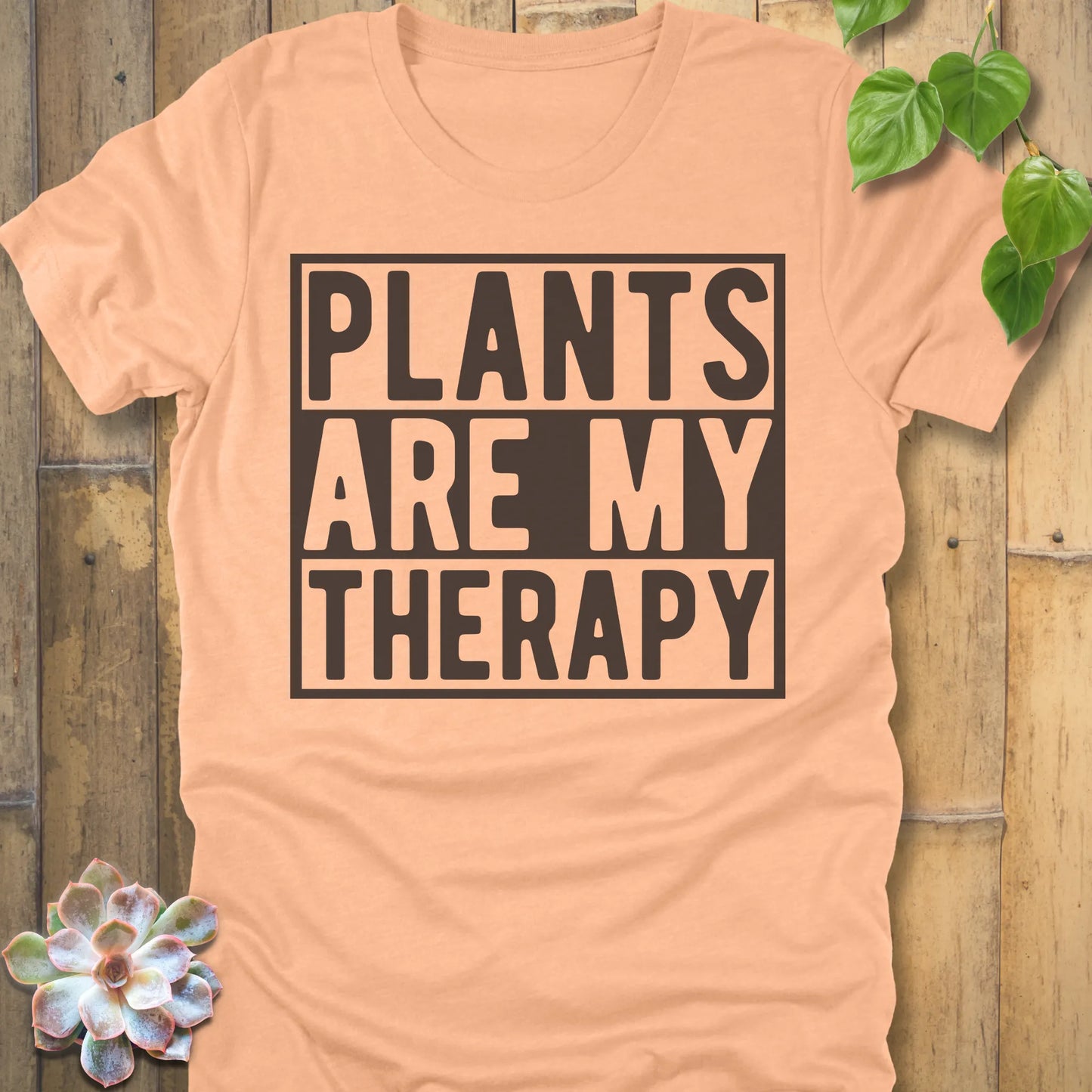Heather Peach t-shirt featuring the design Plants Are My Therapy printed in bold letters, plant lover shirt.