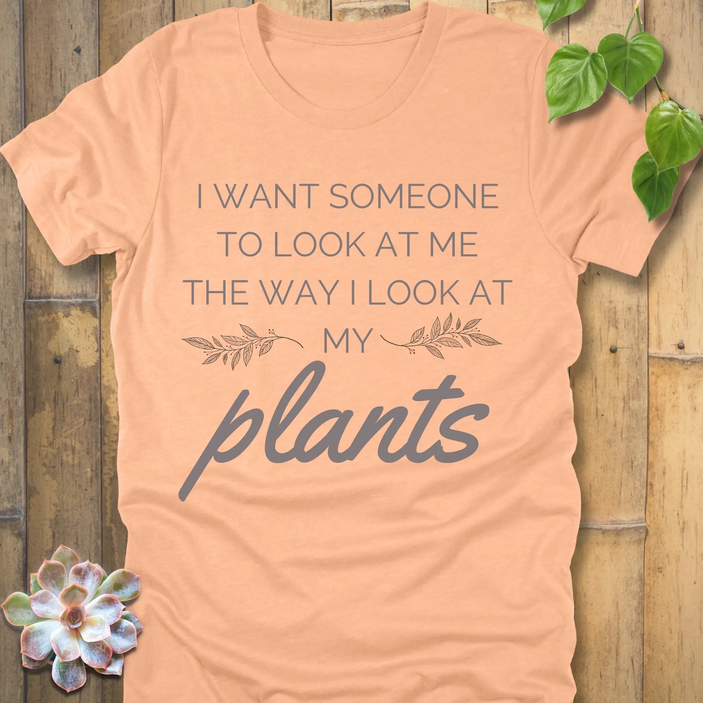 Heather Peach t-shirt with the phrase "I want someone to look at me the way I look at my plants" in bold grey lettering.