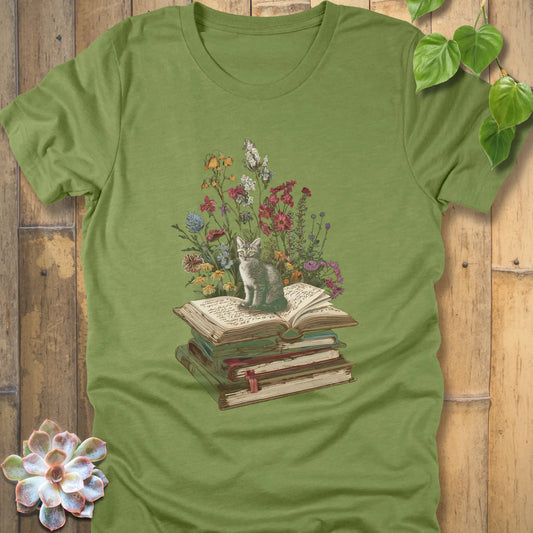 Heather green t-shirt featuring the design Whiskers & Words with a cat sitting on books and flowers, eco-style tee for book and cat lovers.