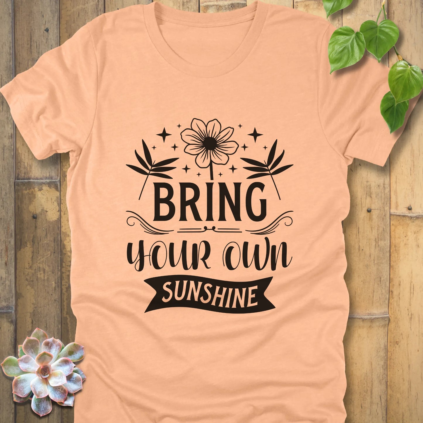 Heather peach t-shirt featuring the design "Bring Your Own Sunshine" printed in black letter and flower