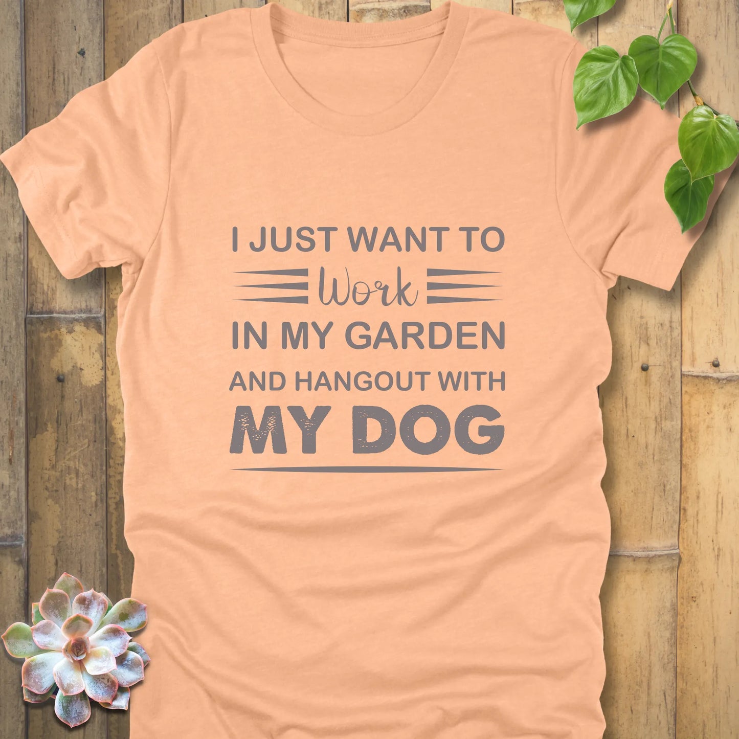 Heather peach t-shirt featuring the design "I just want to work in my garden and hangout with my dog" printed in bold black letters