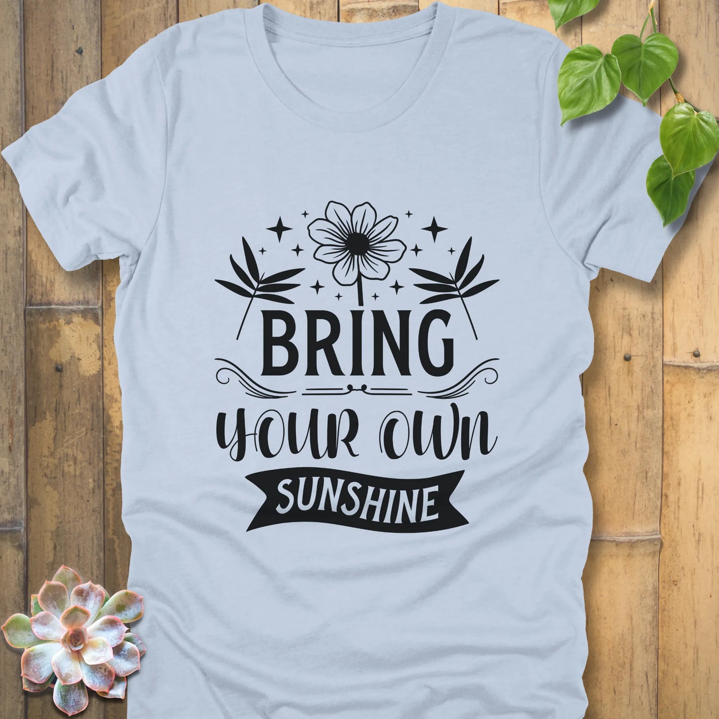 Light blue t-shirt featuring the design "Bring Your Own Sunshine" printed in black letters and flower