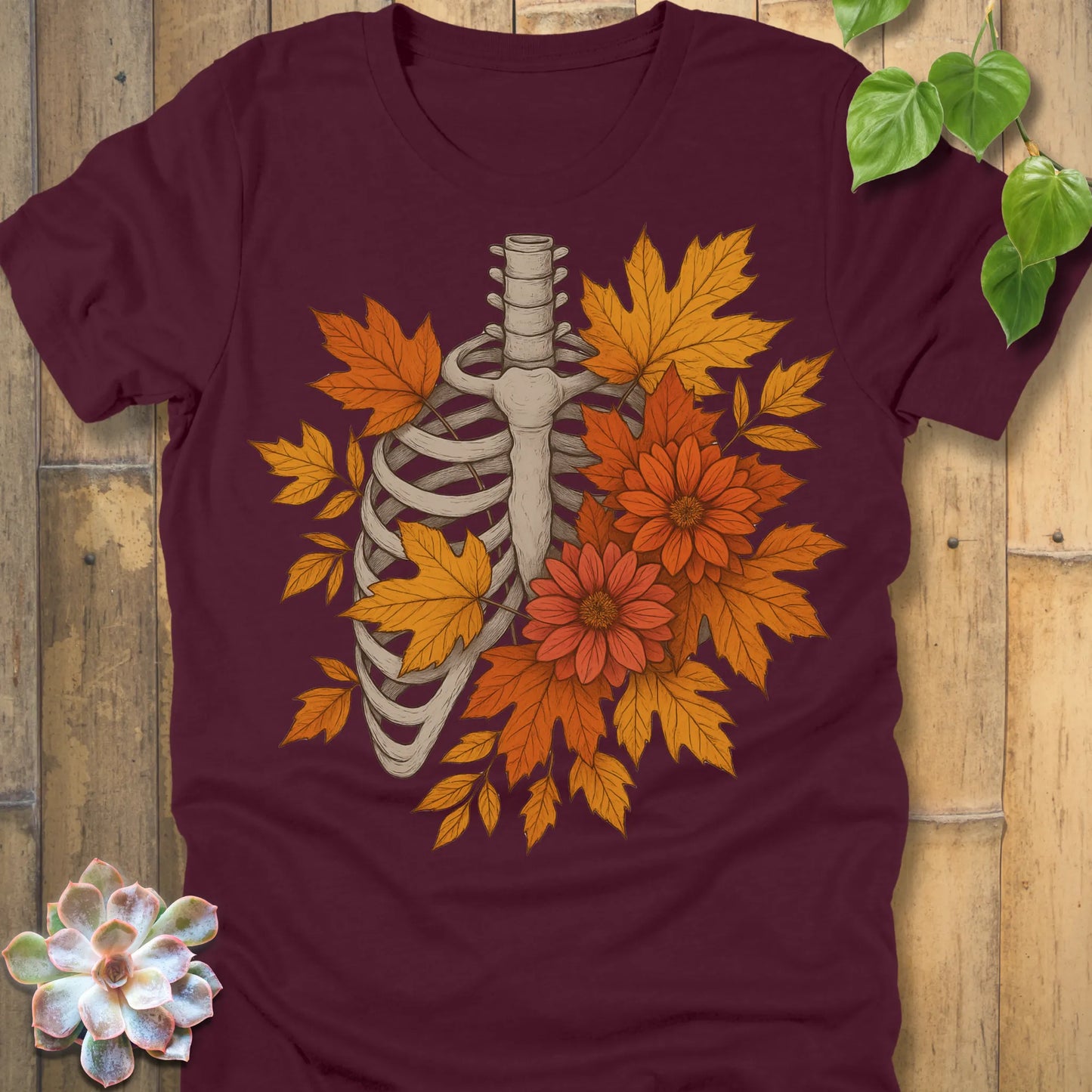 Maroon t-shirt featuring the design Autumn Bones printed Halloween skeleton shirt with flowers and leaves.