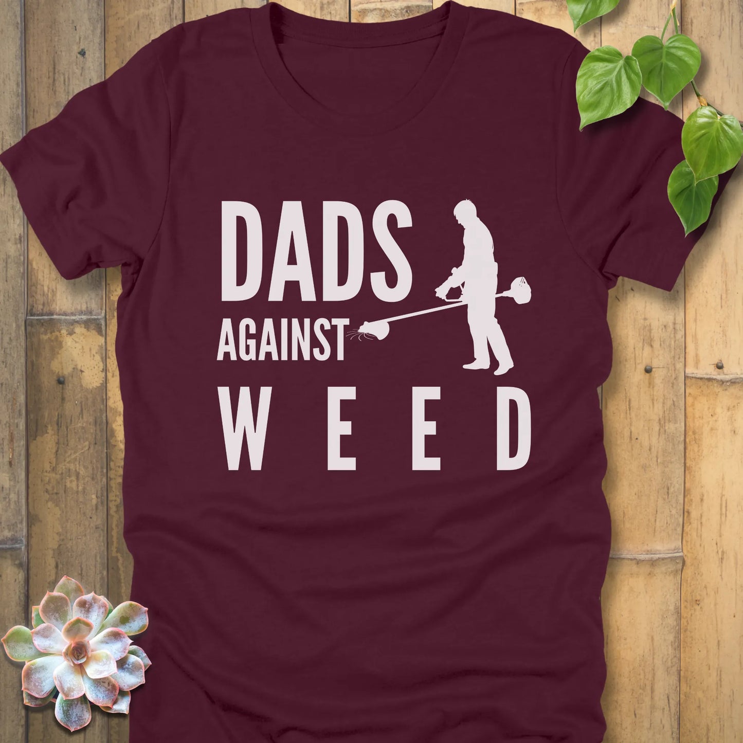 Maroon t-shirt featuring the design Dads Against Weed printed with man mowing.