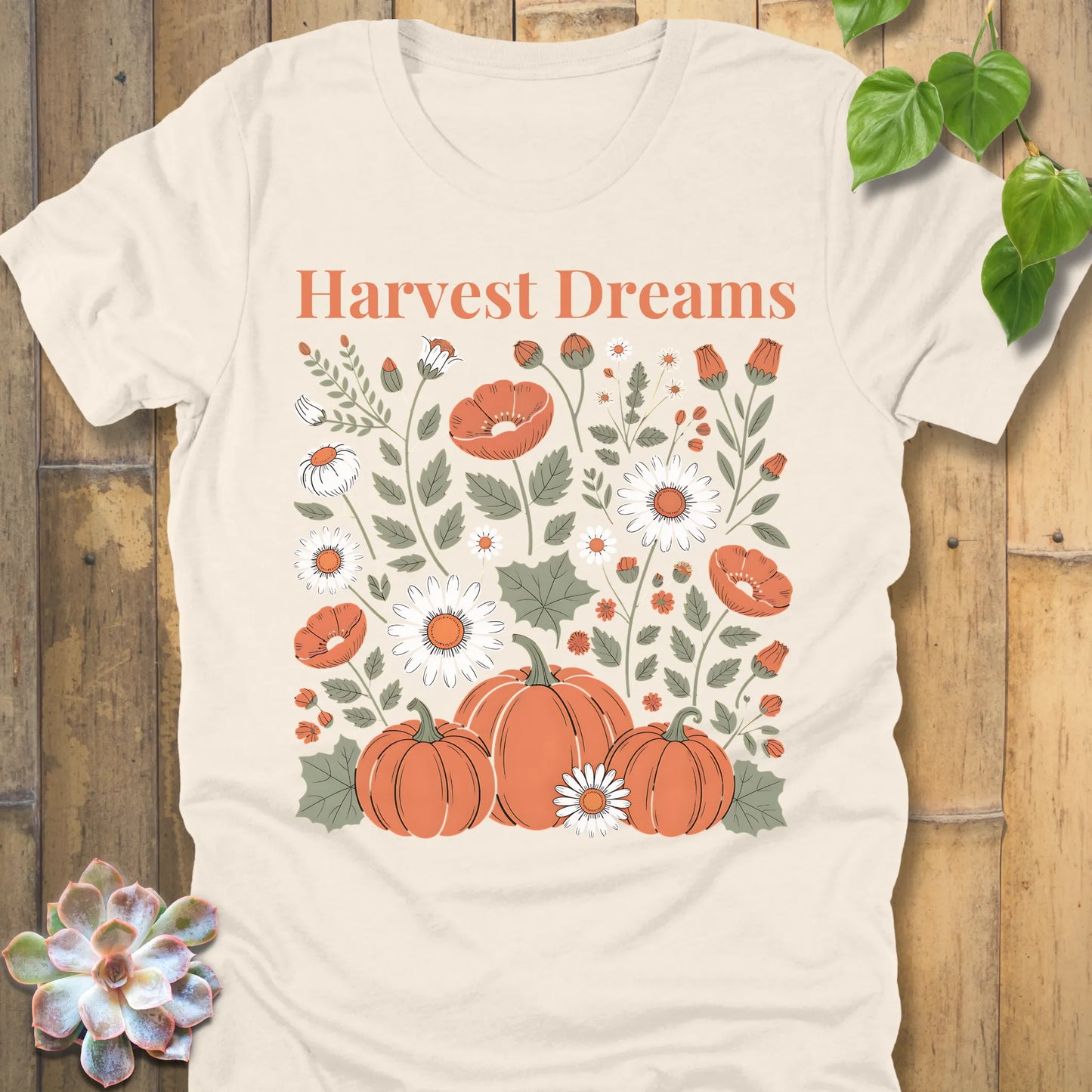 Natural t-shirt featuring the design Harvest Dreams printed in orange letters flowers and pumpkin