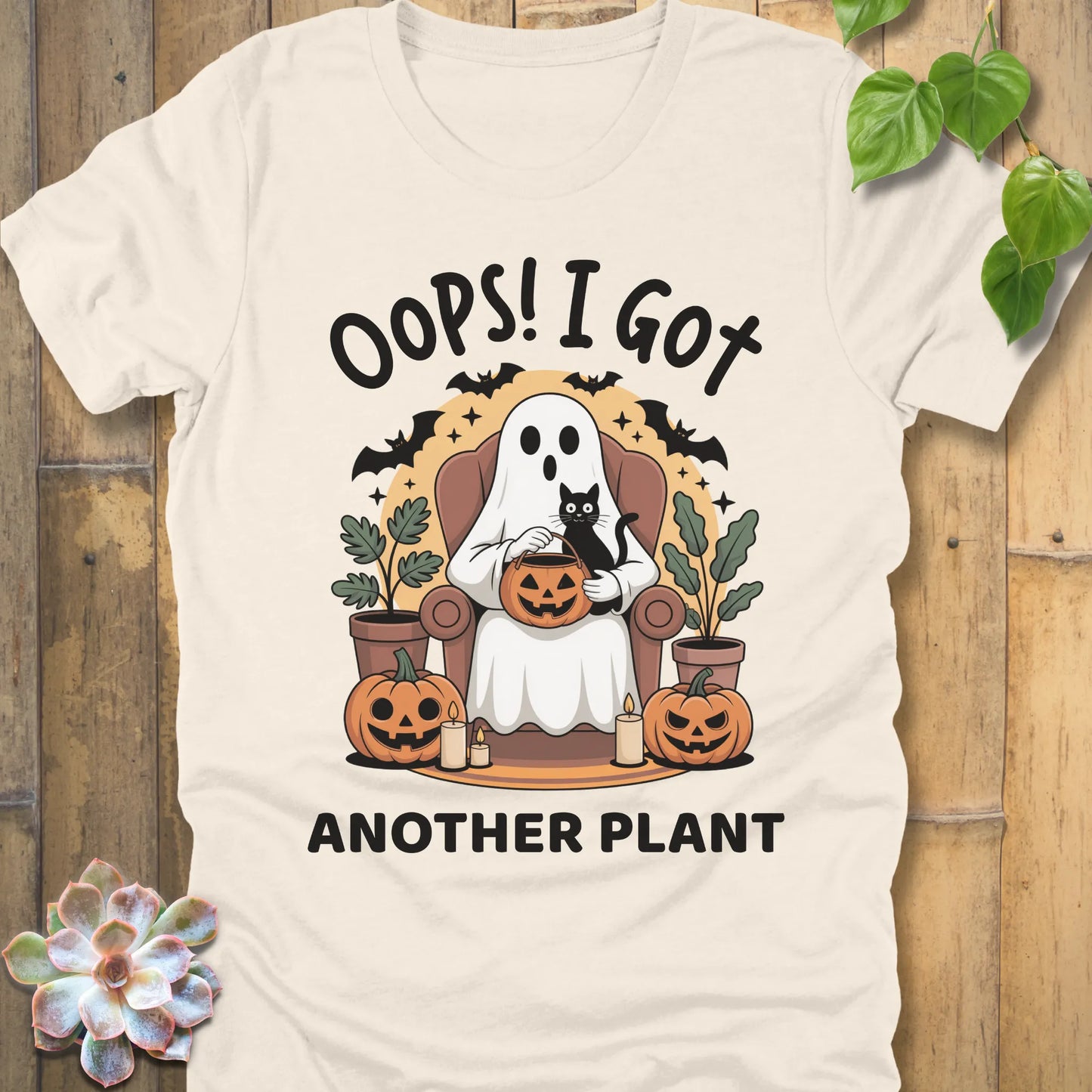 Natural t-shirt featuring the design "Oops! I Got Another Plant" printed in bold black letters, and a ghost, cat, plants, bats and pumpkin