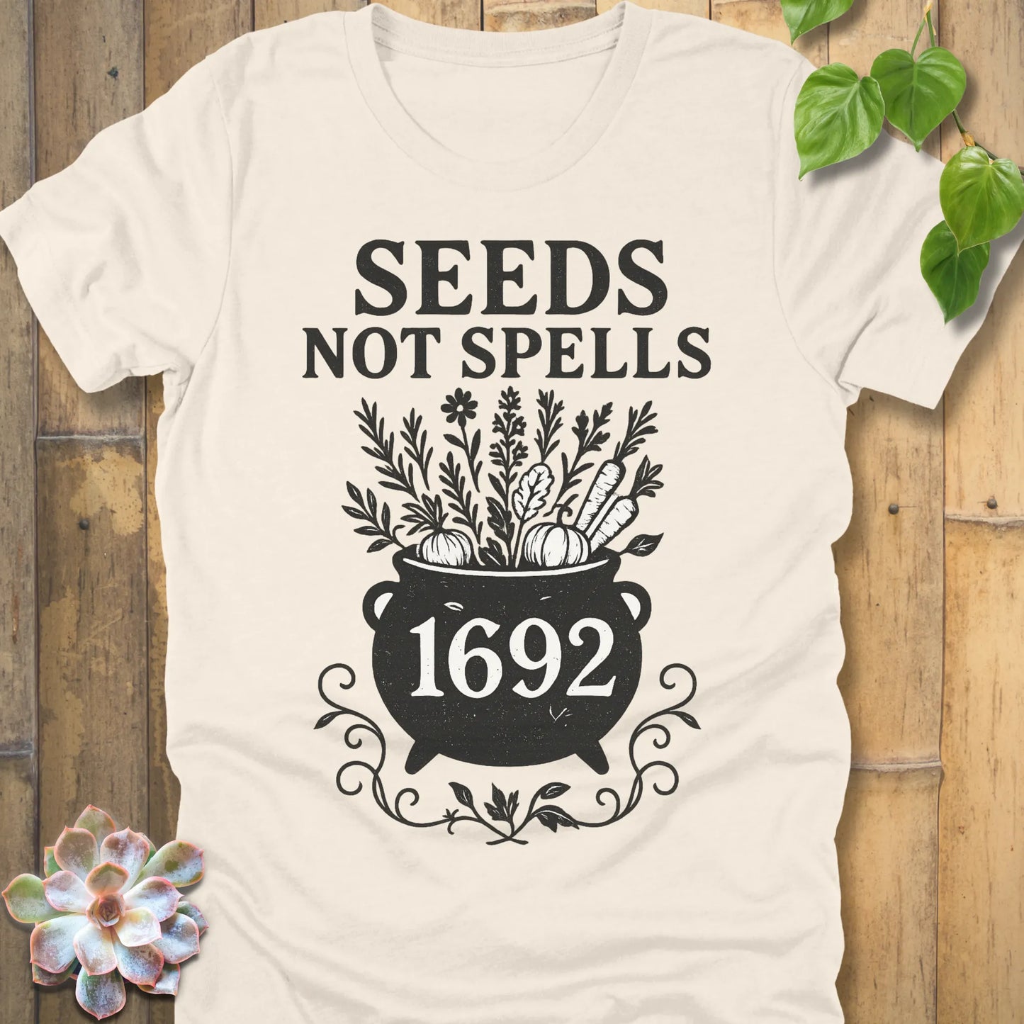 Natural t-shirt featuring the design Seeds Not Spells printed in bold black letters, halloween gardening graphic tee.