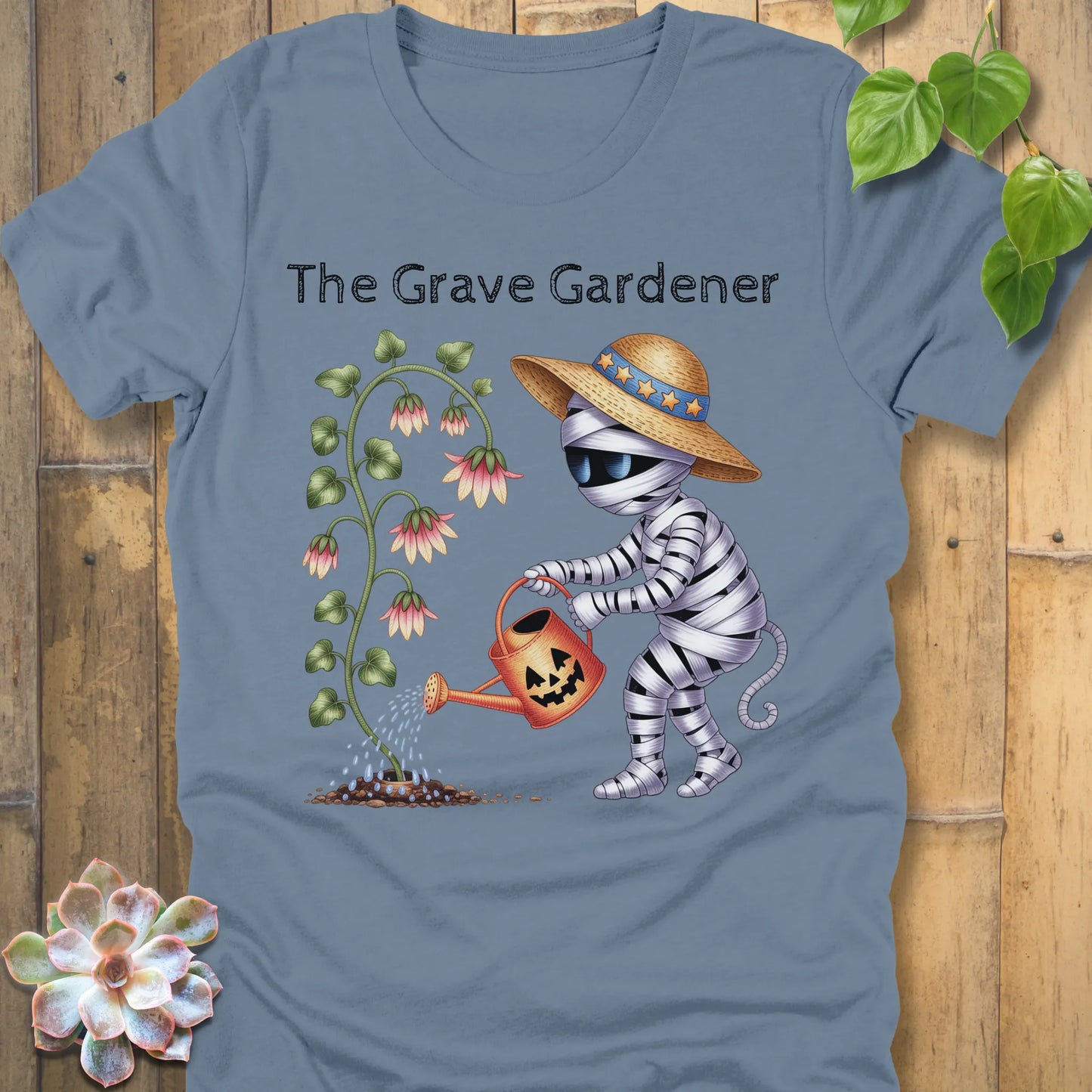 Steel Blue t-shirt featuring the design The Grave Gardener printed in bold black letters and a ghost watering the plant